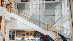 Ένας ευρύχωρος χώρος υποδοχής με μια επιβλητική σκάλα, ένα μπαρ και έναν εντυπωσιακό πολυέλαιο.