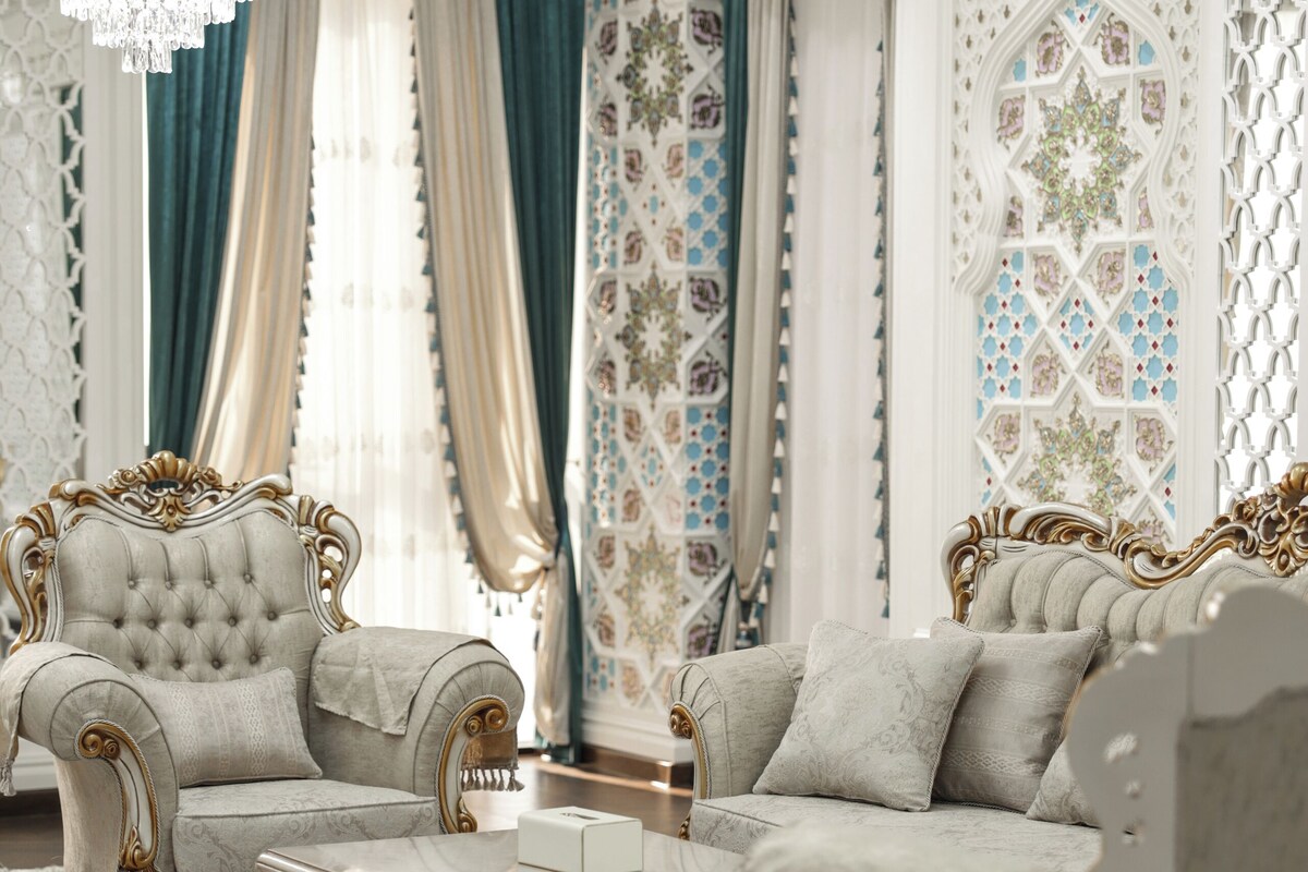 Una habitación lujosa con muebles ornamentados, un candelabro y cortinas decorativas.