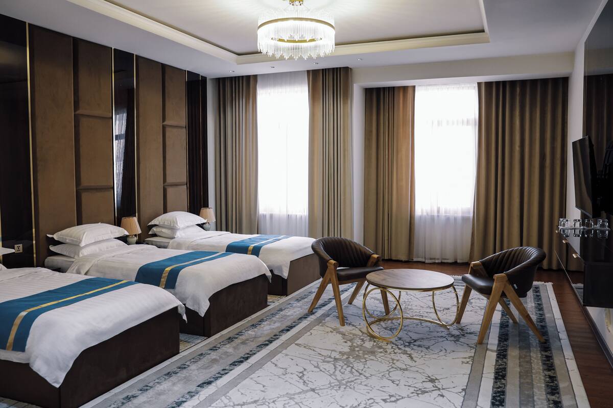 Ein Hotelzimmer mit zwei Betten, einer Kandelaber, einem Fernseher und einem kleinen runden Tisch.