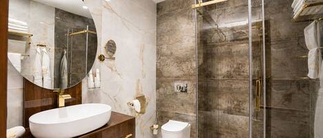 Une salle de bain moderne avec un grand lavabo ovale, un miroir rond, une douche en verre et des murs en marbre.