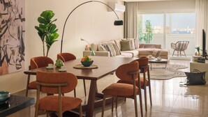 Ein modernes Wohnzimmer mit Essbereich, großen Fenstern und Blick auf die Stadt.