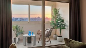 Ein Balkon mit Blick auf die Stadt, ein runder Tisch mit zwei Stühlen und Blumentöpfen.