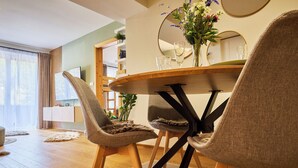 A modern dining area with a round table, two upholstered chairs, a mirror, and a vase with flowers. - Na Kovárně by Interhome (Pec pod Snezkou)