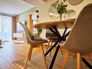 A modern dining area with a round table, two upholstered chairs, a mirror, and a vase with flowers. - Na Kovárně by Interhome (Pec pod Snezkou)