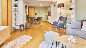 A modern living room with a sofa, a dining table, and a kitchen in the background. - Na Kovárně by Interhome (Pec pod Snezkou)