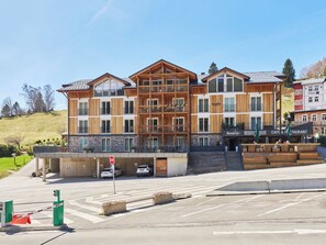 Un hotel de varios pisos con fachada de madera, balcones y una cafetería en la planta baja.