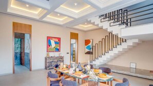 Un'ampia sala da pranzo con soffitto alto, una scala e arredamento moderno.