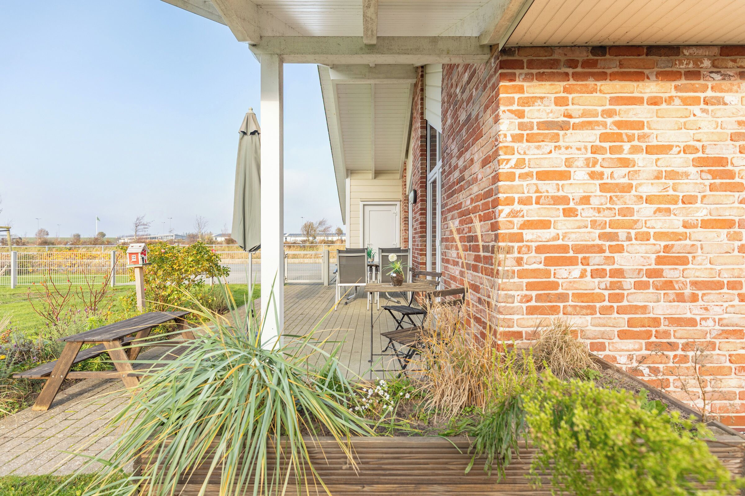 A patio area with a wooden deck, a brick wall, and a covered seating area with a table and chairs.