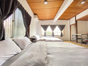 Ein Hotelzimmer mit zwei Betten, Holzbalkendecke und einem Fenster mit Vorhängen.