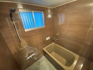 Ein Badezimmer mit einer Badewanne, einer Dusche und einem Fenster mit blauen Vorhängen.