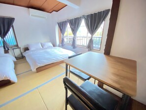 A room with a bed, a table, and a futon.