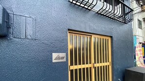 A blue building with a large wooden gate and a small sign. - AkiraHome Haginochaya (Osaka)