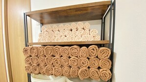 A metal shelf with two white baskets and a wooden shelf holding rolled towels. - AkiraHome Haginochaya (Osaka)