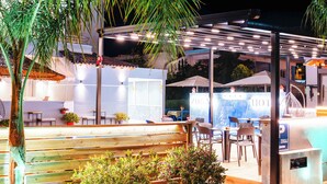 An outdoor pool area with seating, potted plants, and a covered seating area. - Hotel Zogaj (Ksamil)