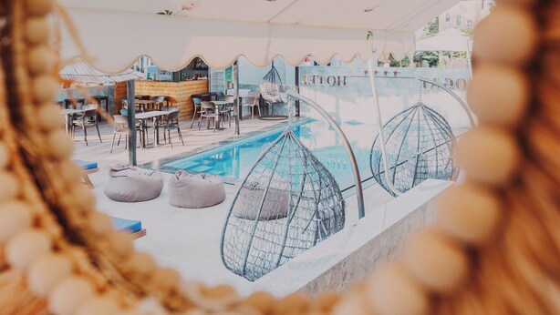 A pool area with lounge chairs and umbrellas, surrounded by a white fence. - Hotel Zogaj (Ksamil)