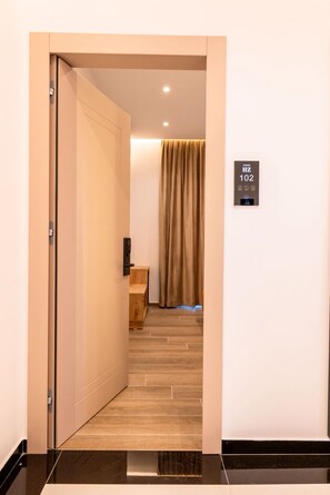 A hallway with a door leading to a room, a sign with room number, and a wooden bench. - Hotel Zogaj (Ksamil)