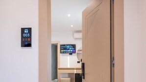 A hallway leading to a room with a flat-screen TV, a small table, and a bench. - Hotel Zogaj (Ksamil)