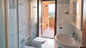 Un baño moderno con cabina de ducha de vidrio, un bidé, un inodoro y un lavamanos.