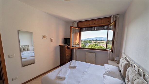 Habitación de hotel con una cama grande, un espejo, una cómoda y una ventana con vistas a la ciudad.