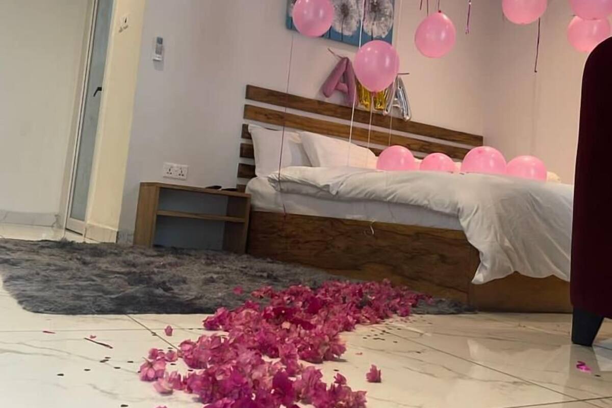 Ein Schlafzimmer mit einem Bett, einem hölzernen Kopfteil, einer Tür und einer Wand mit einem floralen Gemälde.
