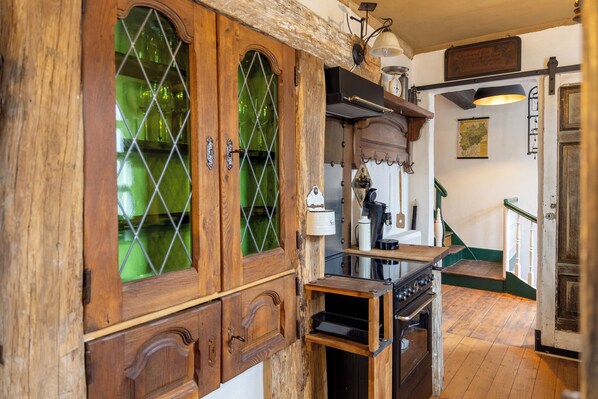 Une cuisine avec des meubles de rangement en bois, une cuisinière et une porte en verre vert.