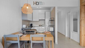 Una cocina moderna con armarios blancos, una mesa de comedor con sillas, una lámpara colgante y un letrero que dice "Home" sobre los armarios.