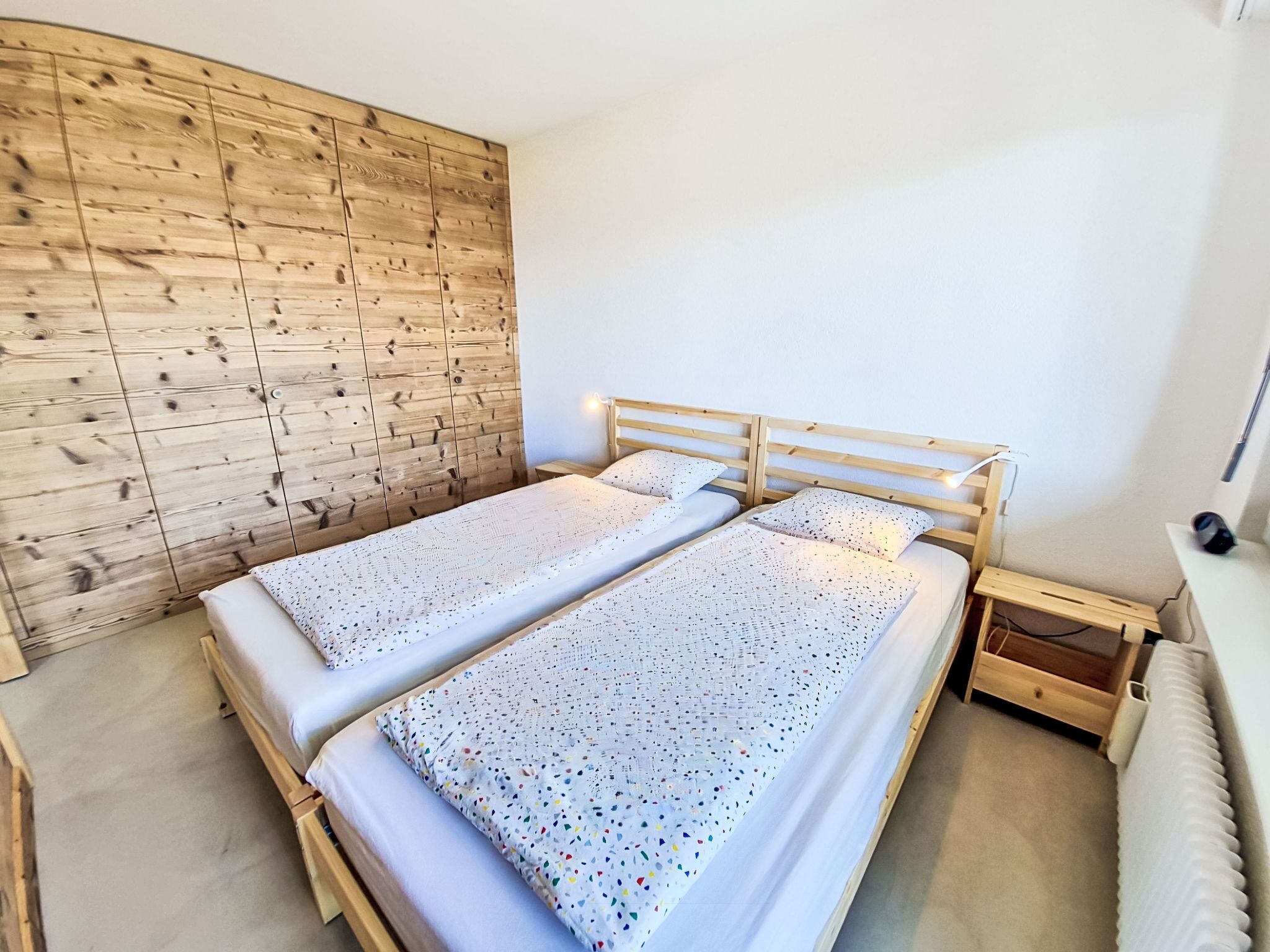 Une chambre à coucher avec deux lits, des têtes de lit en bois, un panneau mural en bois, une table de chevet et une commode.