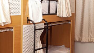 Une chambre avec un lit superposé, une structure en bois, une échelle en métal et un petit tiroir.