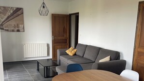 En moderne stue med et træspisebord, en grå sofa og et bybillede på væggen.