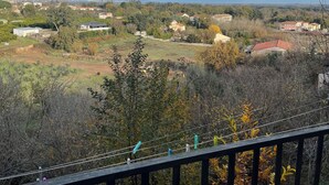 En balkon med udsigt over et boligområde med huse og træer.