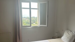 Et soveværelse med seng, et vindue, en radiator og en pendel.