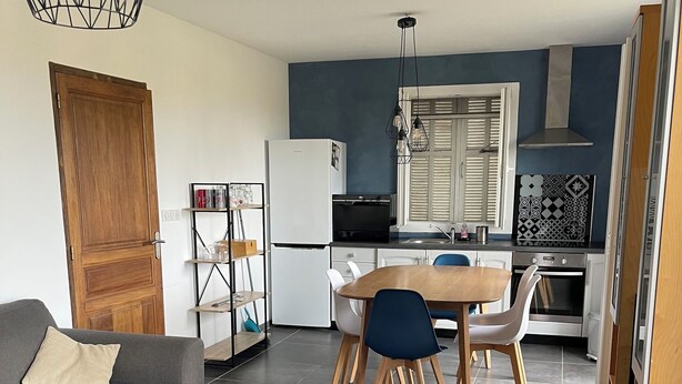 En moderne stue med en grå sofa, et træbord og et spiseområde med et træbord og blå stole.