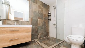 Un baño moderno con ducha, inodoro y tocador con cajones.