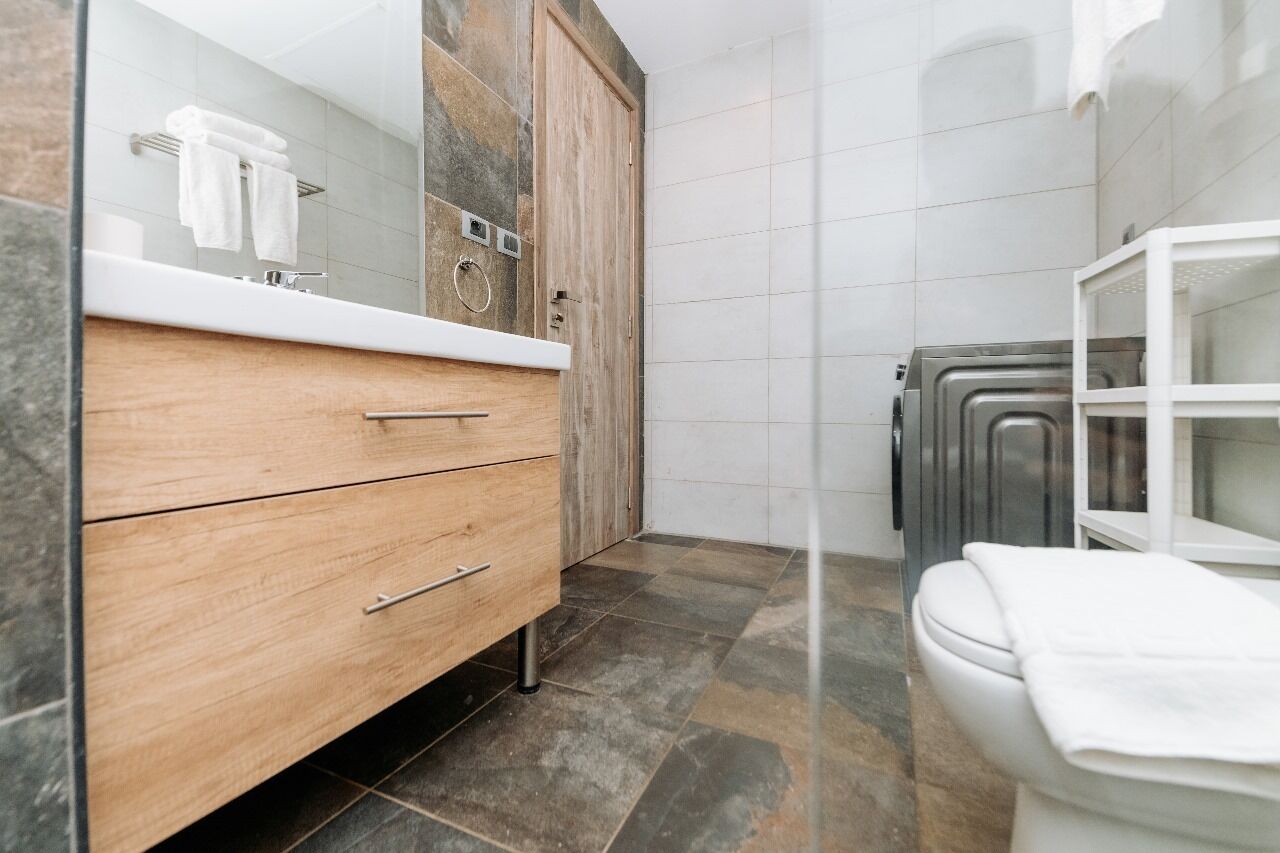 Un bagno con un mobiletto vanità in legno, un lavandino bianco e un box doccia in vetro.