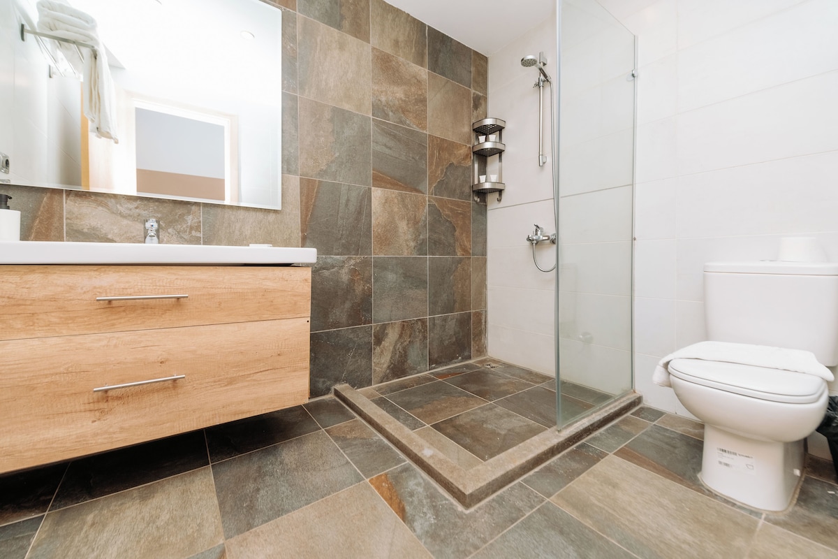 A modern bathroom with a shower, toilet, and vanity with drawers.