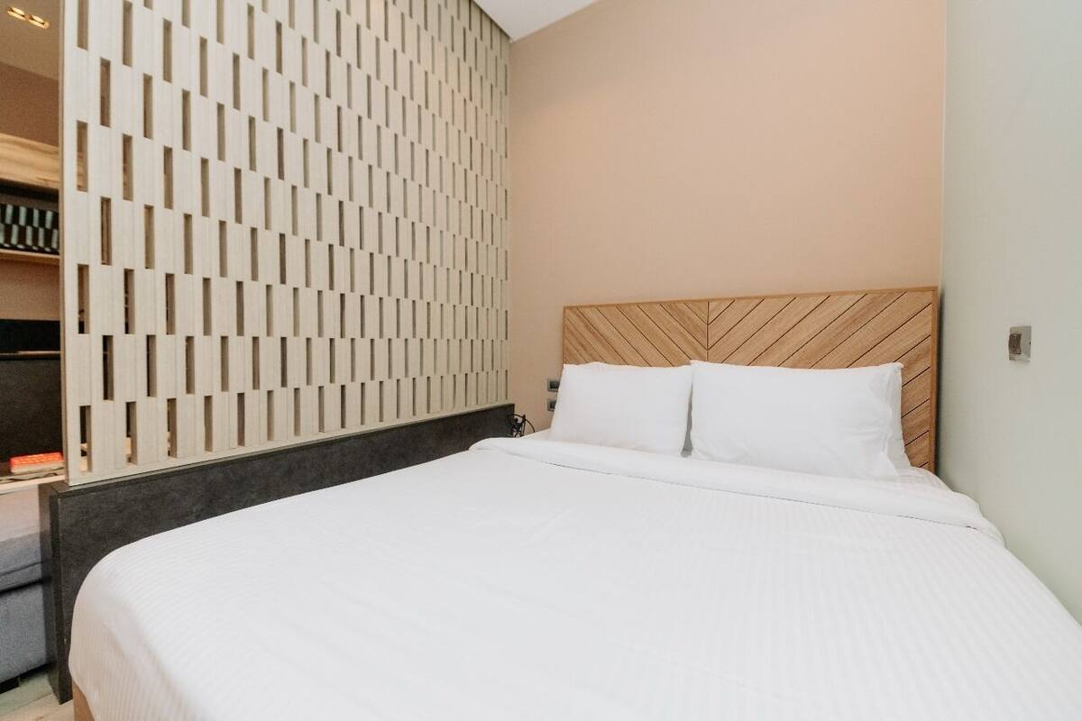 Una habitación de hotel moderna con una cama grande, un cabecero de madera y un panel decorativo en la pared.