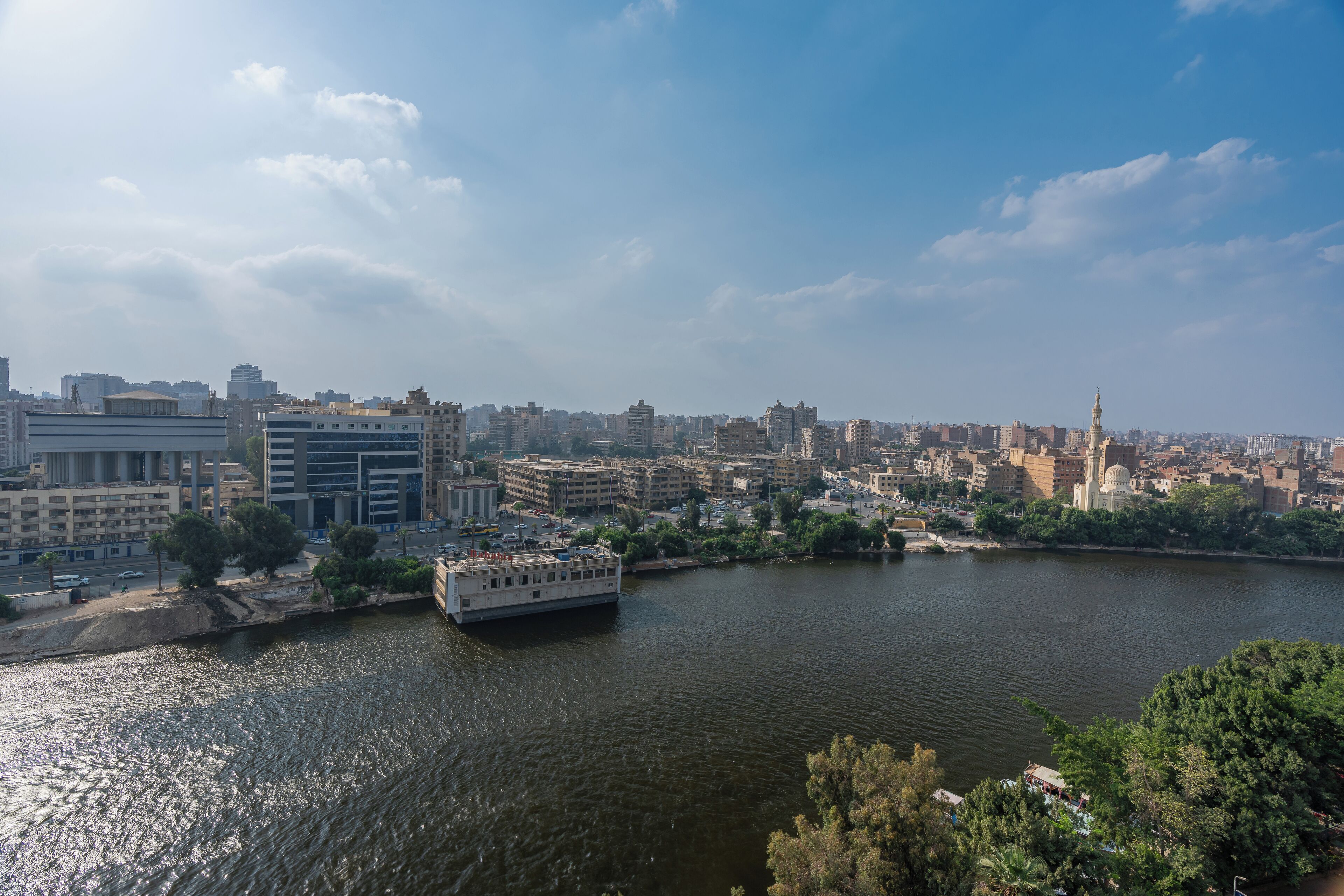 Un río con una barca, rodeado de edificios y árboles.