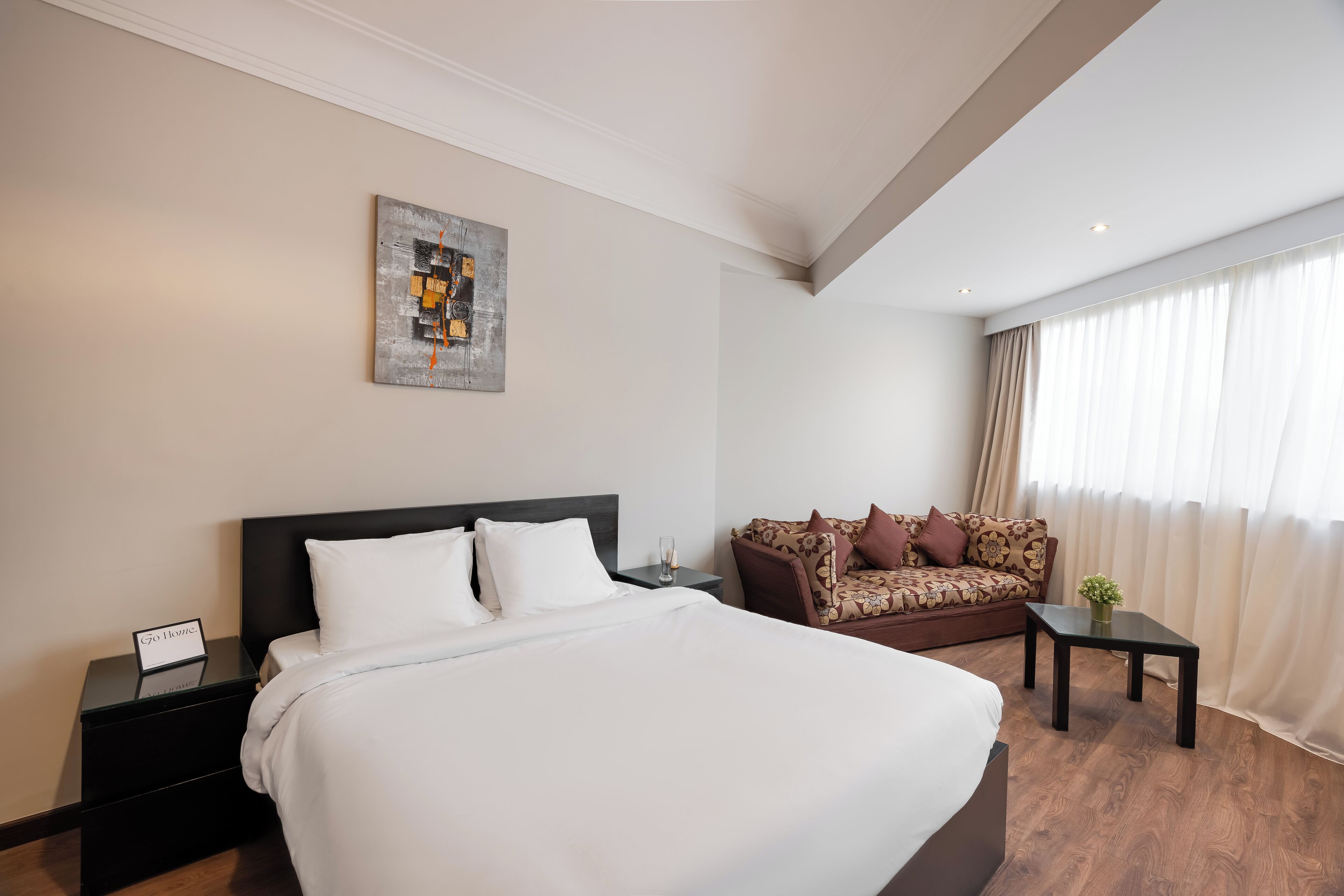 Een hotelkamer met een groot bed, een bank, een klein tafeltje en een schilderij aan de muur.