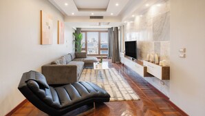 A modern living room with a sofa, a recliner, a TV, and a marble wall. - Brassbell Zamalek Om Kolthoom (Cairo)