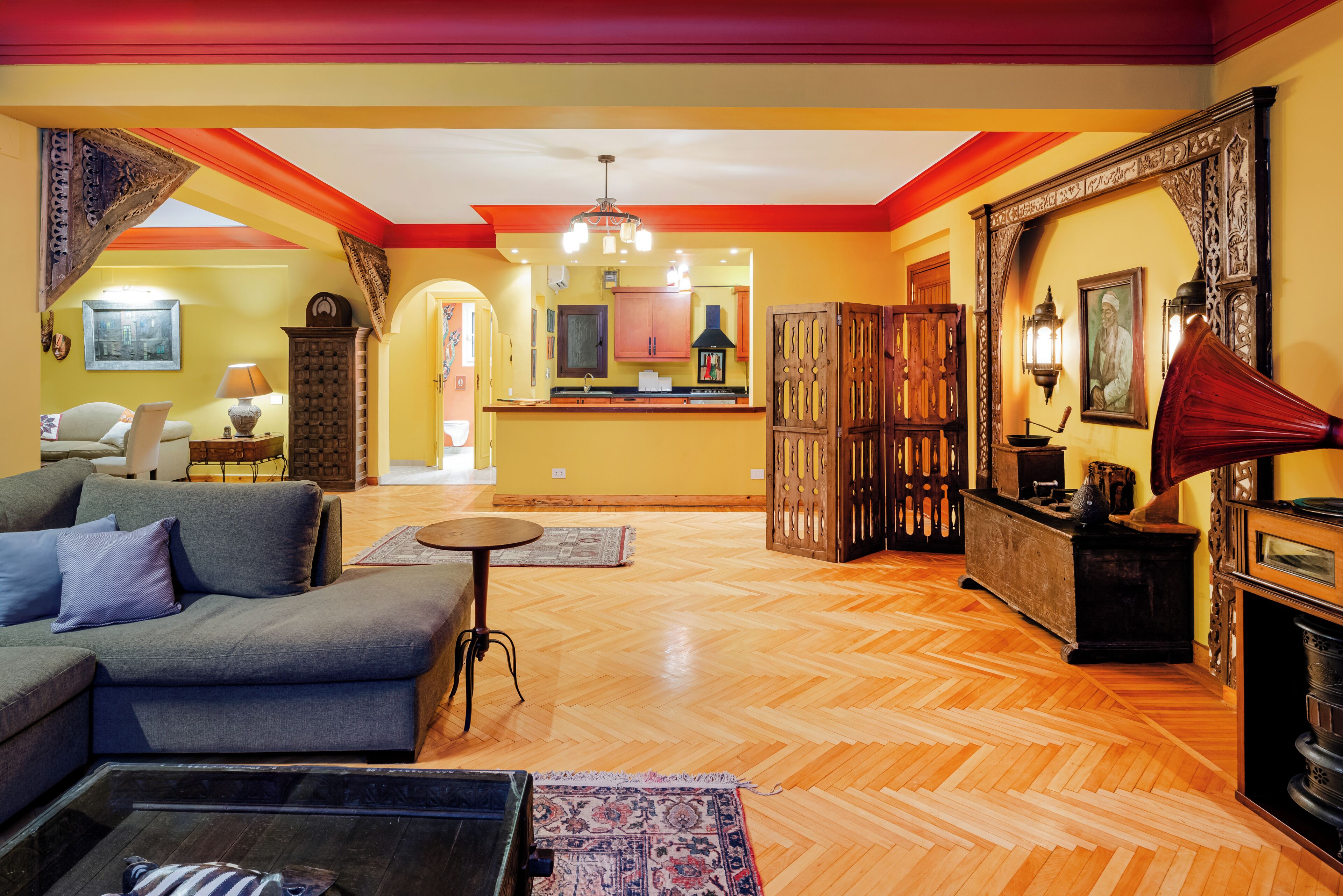 Una sala de estar con sofá, una mesa de centro, chimenea y una cocina al fondo.