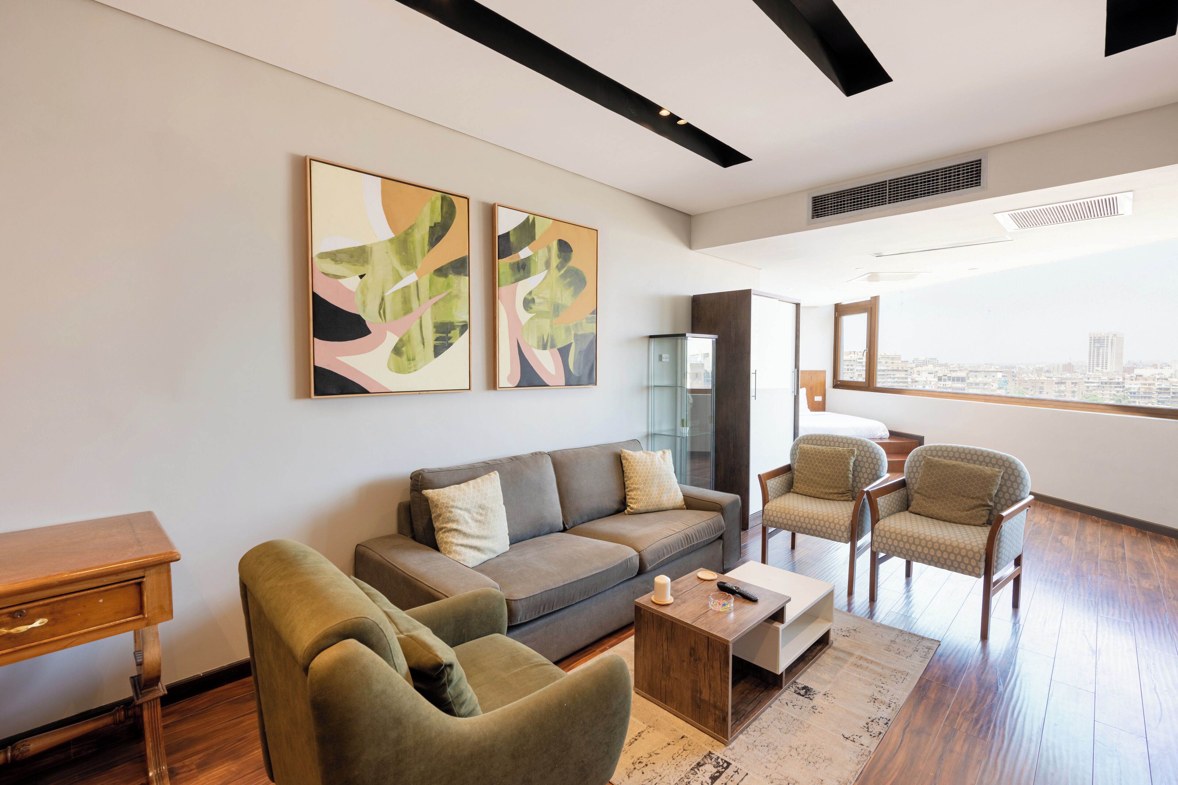 A modern living room with a sofa, armchairs, a coffee table, and abstract art on the wall.