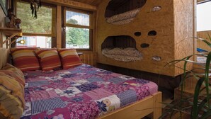 Ein gemütliches Zimmer mit einem hölzernen Bett, einem Fenster mit Jalousien und einem einzigartigen Wanddesign mit Rundaussparungen.