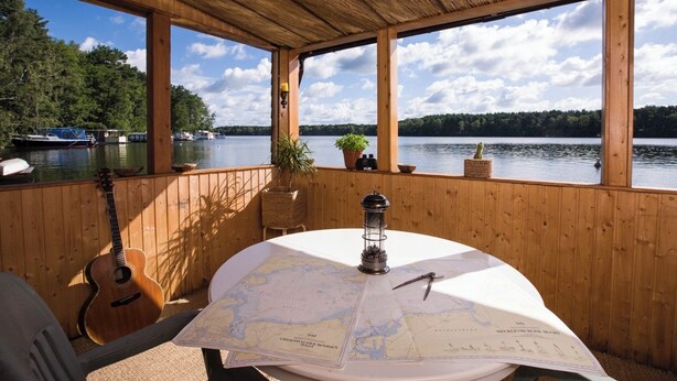 Eine Holzdielen-Terrasse mit Tisch, Gitarre, Karte und Laterne.