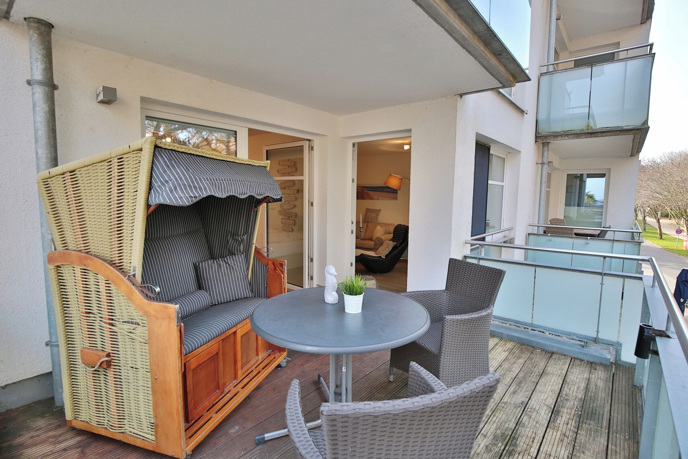 A balcony with wicker furniture, a round table, and a potted plant.