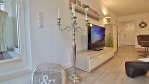 Ein modernes Wohnzimmer mit Fernseher, einem Kerzenleuchter, einer Bank und einem Sofa.