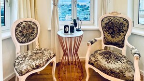A corner room with two ornate chairs, a small table with a cup and a plant, and a large window with a view of a cityscape. - Comfortable 3BR Stay Kaufpark Area (Vienna)