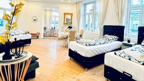A spacious hotel room with two beds, a dining area, and large windows. - Comfortable 3BR Stay Kaufpark Area (Vienna)