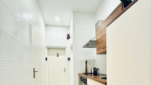 A kitchen with white cabinets, a marble floor, and a door marked with the number 3. - Comfortable 3BR Stay Kaufpark Area (Vienna)