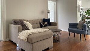 Un soggiorno con un divano color beige, una poltrona blu e un piccolo tavolino rotondo.