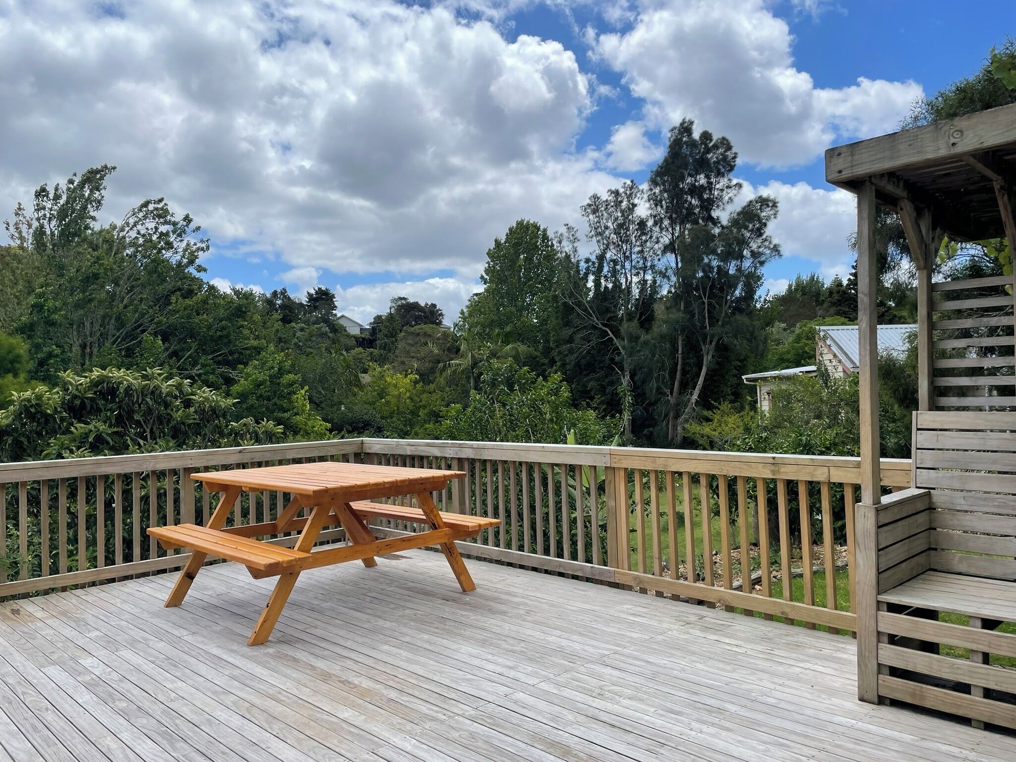 A wooden deck with a picnic table and a wooden pergola.